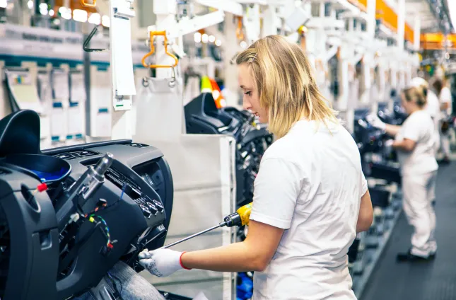 woman working on a car cockpit board assembly line