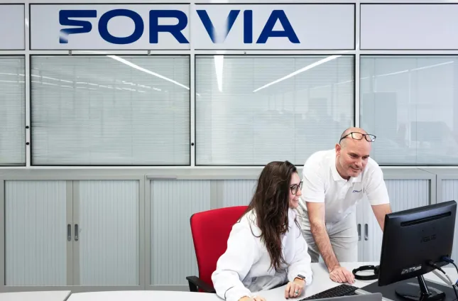 man and woman colleague discussing at a desk in front of a computer