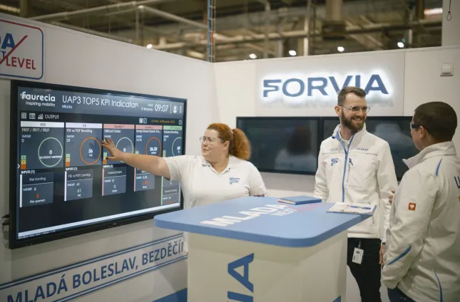a woman and 2 men discussing near monitoring screens in a modern plant